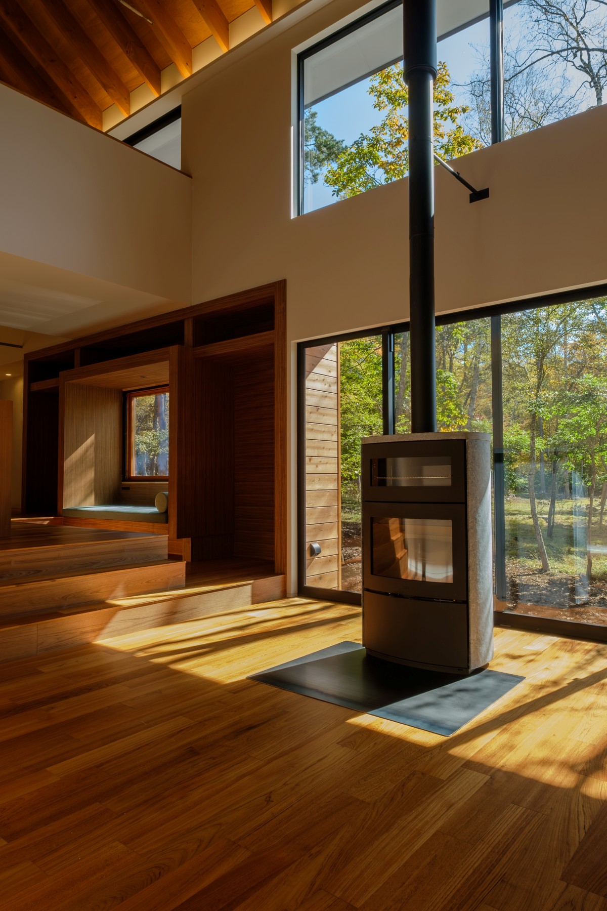 蓼科八ヶ岳地域に建つ、内装をチーク材と木材で仕上げた高級別荘。薪ストーブがあるリビング吹き抜け空間から望む白樺の景色